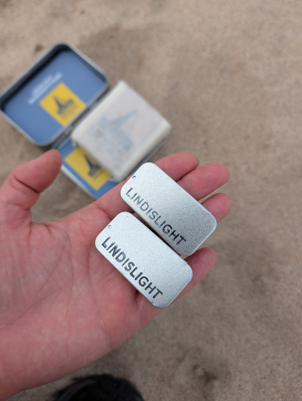 Two Lindislight balm tins held in hand